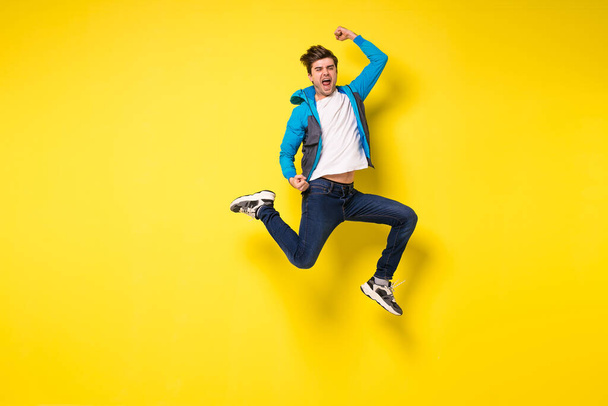 Mid-air shot of handsome young man jumping and gesturing, showing excitment - Zdjęcie, obraz
