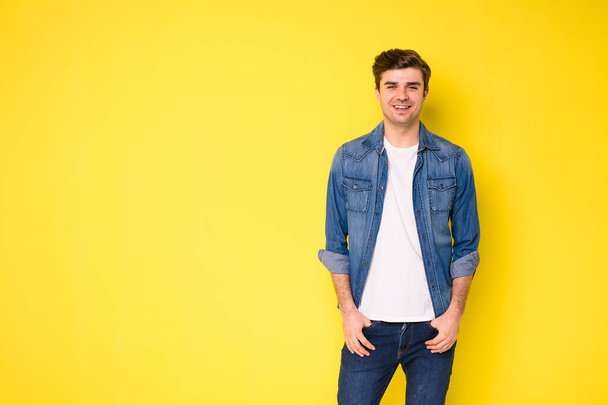 smiling optimistic person in cool jeans shirt standing on yellow background - Fotoğraf, Görsel