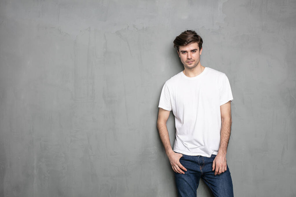 normal young man standing on a grey background concrete wall - Foto, Bild