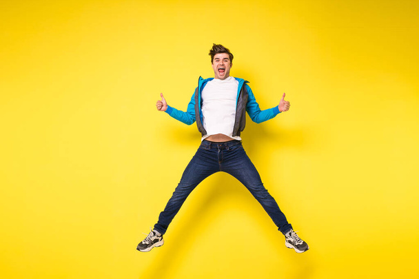 Mid-air shot of handsome young man jumping and gesturing, showing excitment - Foto, Imagen