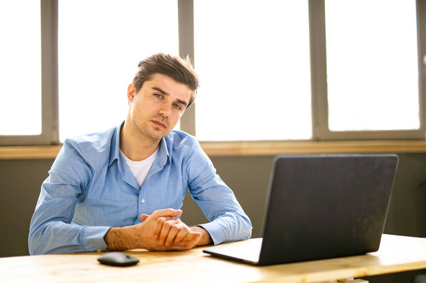 Portrait of young man sitting at his desk in the office - Foto, Imagem