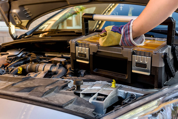 Mechaniker hält Werkzeugkiste neben kaputtem Auto - Foto, Bild