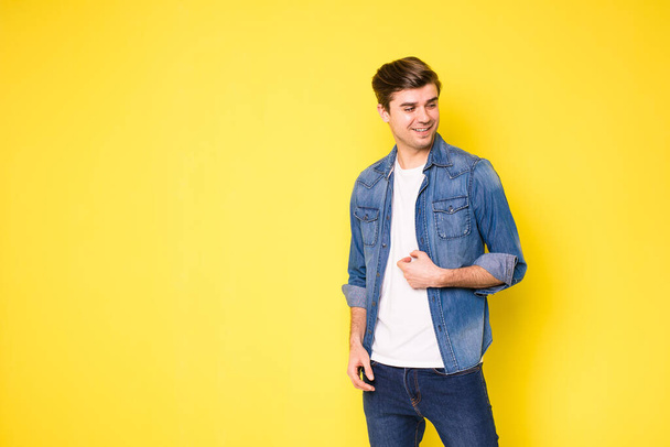 simple and cool guy in jeans looking to side, on yellow background - Fotó, kép