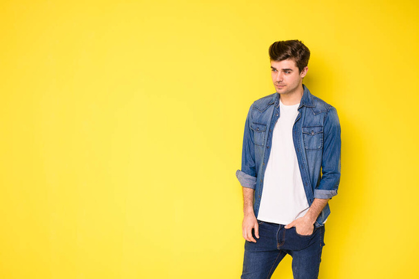 cool handsome young men in jeans outfit standing on yellow background - Photo, image