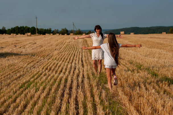 mooie vrouw van middelbare leeftijd en haar tienerdochter rennen over het veld om elkaar te ontmoeten - Foto, afbeelding