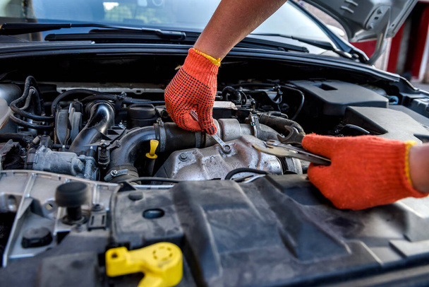 Human hands with wrenches in protective gloves upon car engine - Photo, Image