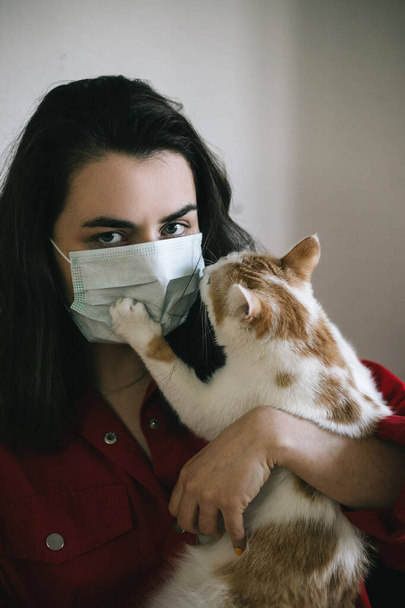 Tyttö lääketieteellisessä naamiossa kissan kanssa
 - Valokuva, kuva
