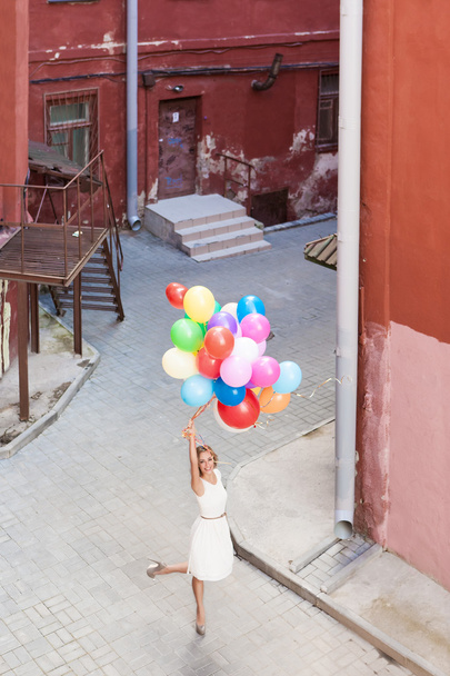 Beautiful lady in retro outfit holding a bunch of balloons - Foto, imagen