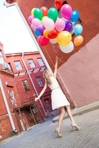 Beautiful lady in retro outfit holding a bunch of balloons - Photo, Image