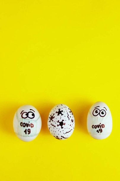 Eeaster symbol eggs in medical masks and painted coronavirus bacteria on yellow background, space for text, vertical view. Easter quarantine concept for Easter holiday due to coronavirus epidemic. - Фото, изображение