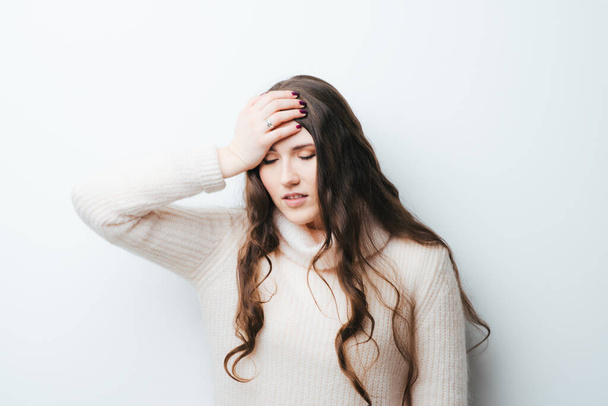 beautiful long-haired girl had a headache and holding his head with hands on a white background - Фото, зображення