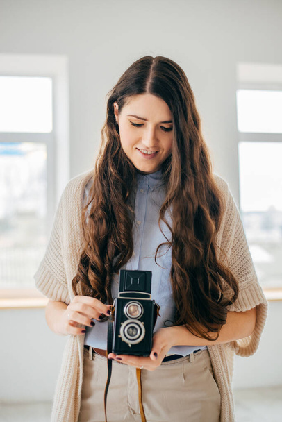 на белом фоне молодая девушка с длинными волосами со старой камерой
 - Фото, изображение