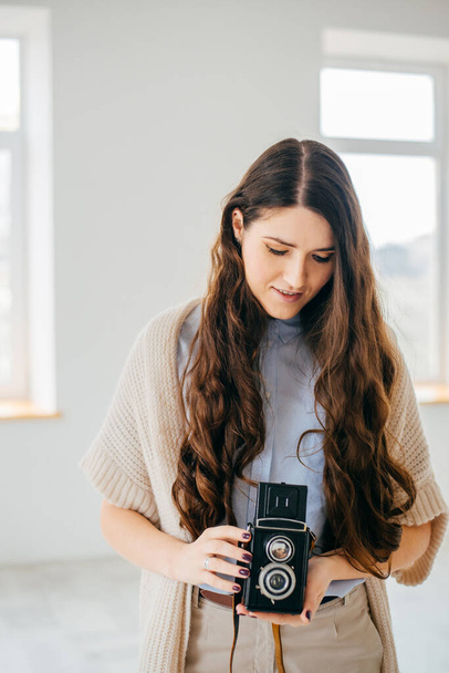 on a white background young girl with long hair with an old camera - Foto, imagen