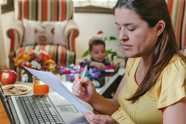Madre che lavora a casa mentre suo figlio gioca
 - Foto, immagini