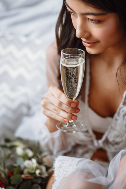bride in her underwear with a glass of champagne on the bed - Foto, Bild