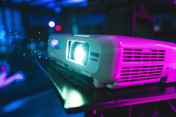 A closeup of a projector under the colorful lights with a blurry background - Foto, Imagem