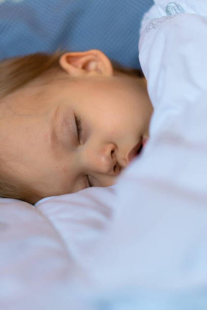 Piccolo bambino biondo sta dormendo nel suo letto
 - Foto, immagini