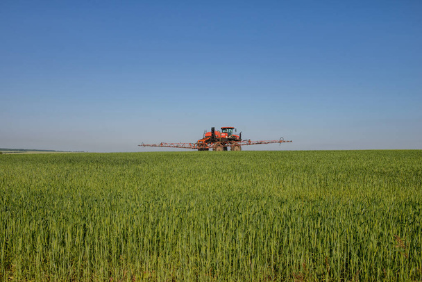 Landbouwmachines. Een zelfrijdend sproeiapparaat werkt in een veld onder een blauwe lucht. Rusland. Tatarstan. 3 juli 2019. Zelfrijdende sproeier - Foto, afbeelding