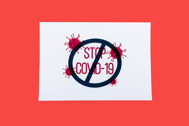 top view of paper with stop covid-19 lettering isolated on red  - Photo, Image