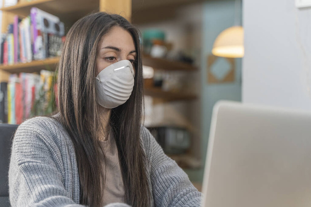 Coronavirus. Business woman working from home wearing protective mask. Business woman in quarantine for coronavirus wearing protective mask. Working from home.  Cleaning her hands with sanitizer gel.  - Photo, Image