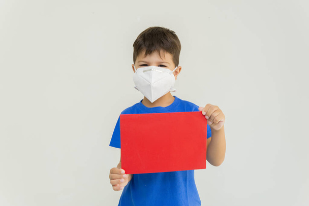 Кавказький хлопчик носить хірургічну маску для запобігання респіраторним захворюванням, що містять пусті аркуші. Обличчя маски для захисту коронавірусу спалаху. Обличчя проти вірусу, хвороби, епідемії, грипу. COVID-19. - Фото, зображення