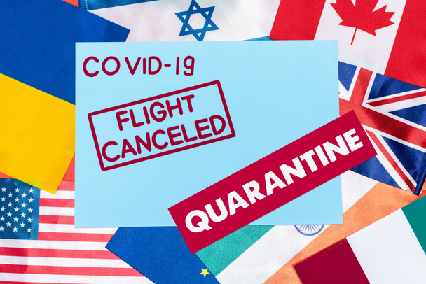 top view of blue envelope with covid-19, flight canceled and quarantine lettering on different flags - Photo, Image