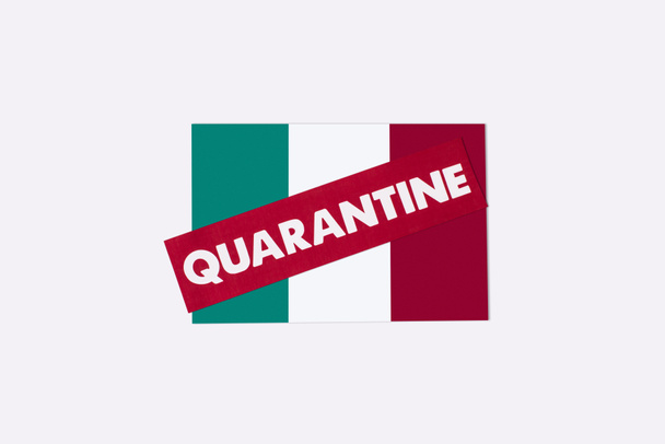 bovenaanzicht van rode kaart met quarantaine letters op Italiaanse vlag geïsoleerd op wit  - Foto, afbeelding