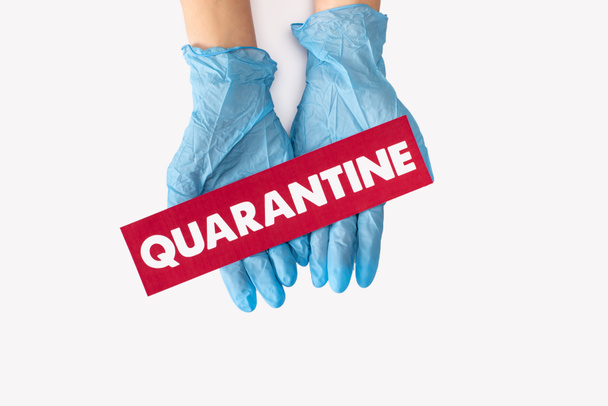 top view of doctor in latex gloves holding card with quarantine lettering isolated on white  - Foto, Imagem