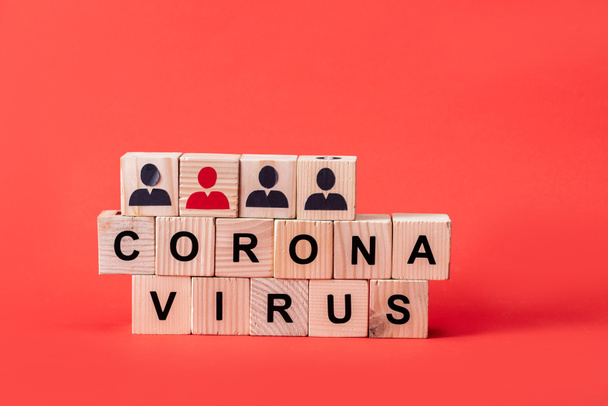 wooden cubes with coronavirus lettering and people icons on red  - 写真・画像