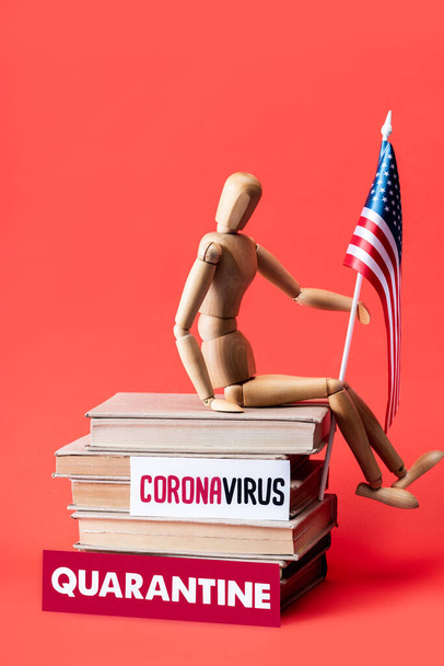 wooden doll with flag of america on books near cards with quarantine and coronavirus lettering on red  - Φωτογραφία, εικόνα