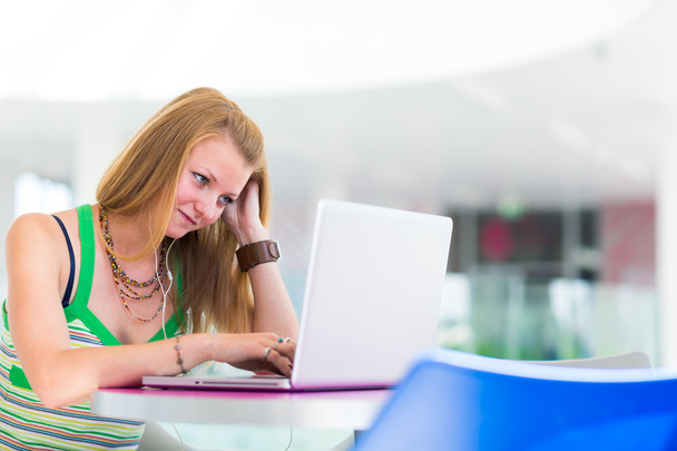 Красивая студентка колледжа, работающая на ноутбуке
 - Фото, изображение