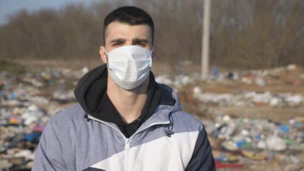Guy wearing protective mask from virus outdoor. Portrait of young man with medical face mask stands at nature. Concept of health and safety life from coronavirus and pandemic. Close up - Footage, Video