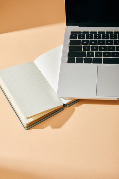 high angle view of opened blank notebook and laptop on beige background - Photo, Image