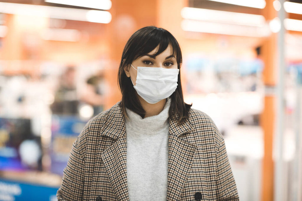 Aasialainen nainen lääketieteellisessä naamiossa kävelemässä ostoskeskuksessa ostoksilla yksin. Viruksen käsite. Terveydenhuolto
.  - Valokuva, kuva