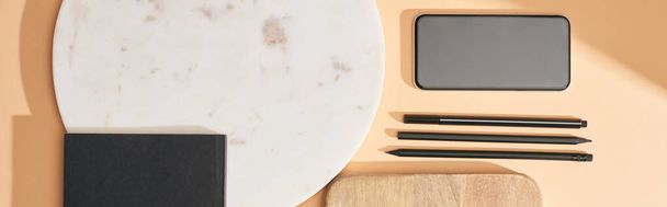 panoramica di tavole in legno e marmo, smartphone, notebook e penne su sfondo beige
 - Foto, immagini