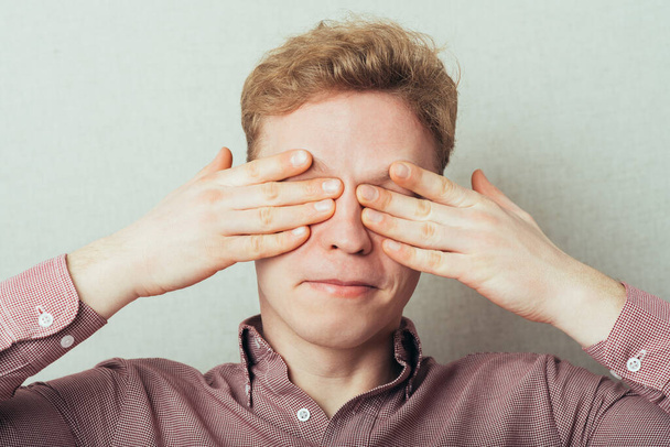 young attractive male cover eyes with his hands - Foto, afbeelding