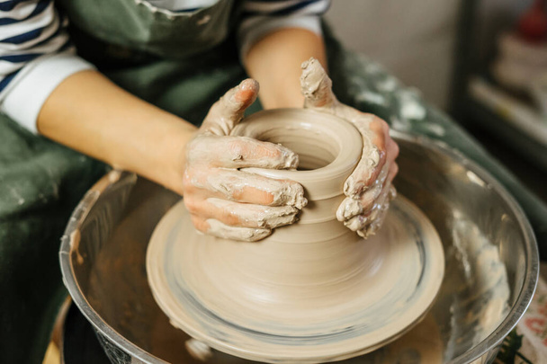 Hands of potter making clay pot on potter's wheel. Ceramics and pottery at the workshops.  - Foto, Imagem