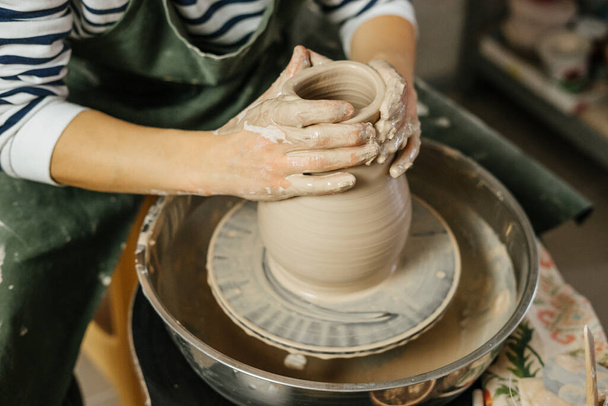 ろくろで土鍋を作る陶芸家の手。粘土の湿式花瓶の形。陶芸工房で手作り鍋。陶芸、陶芸の技術。アートコンセプト. - 写真・画像