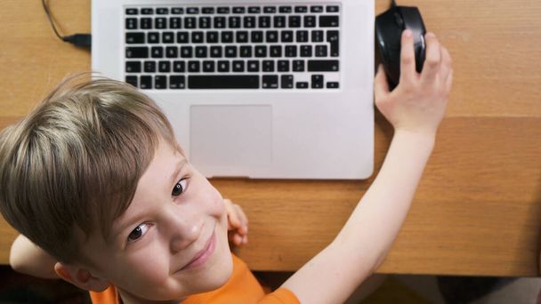 Söpö poika opiskelee kotia tietokoneensa takana. Lapsi nauttii kotitehtävistään. Kotiopetuksen käsite
.  - Valokuva, kuva