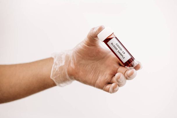 hand with glove taking a vial of blood sample infected with covid-19, medicine concept and protection against viruses and bacteria - Photo, Image