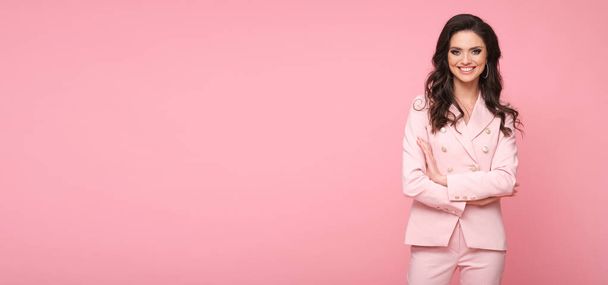 Beautiful brunette model in stylish pink suit isolated on pink background. - Foto, imagen