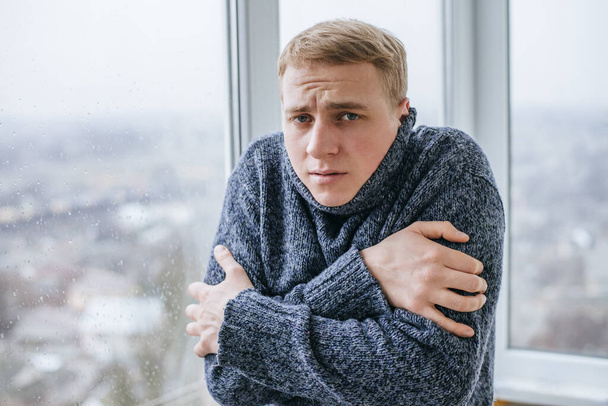 Young man feeling cold in flat near the window - Fotó, kép