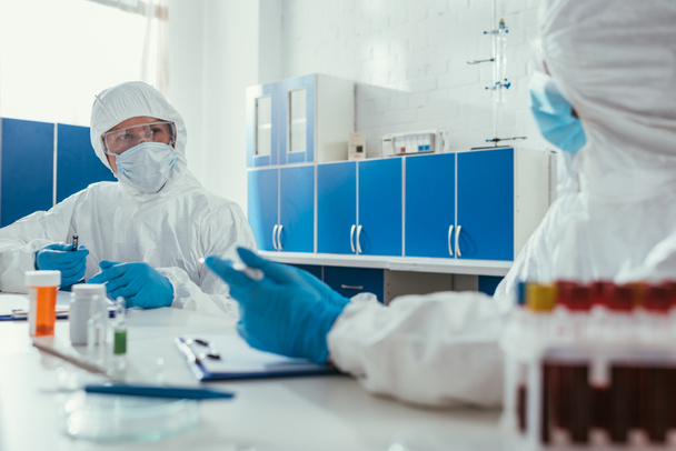 deux biochimistes parlant en laboratoire près des éprouvettes avec des échantillons de sang
 - Photo, image