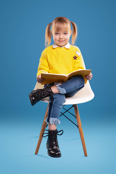 Cute preschooler reading book on chair - Фото, изображение