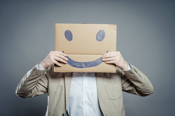 Junger Mann mit einem fröhlichen Smiley-Karte halb bedeckt Gesicht - Foto, Bild