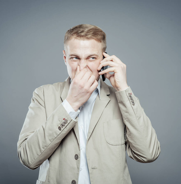 young business man conversation over the cellphone, covers his nose hand - Φωτογραφία, εικόνα