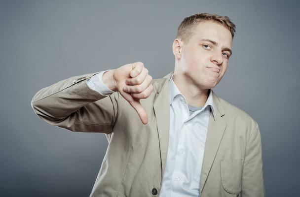 Close-up of a disappointed young business man showing thumb down sign - Фото, изображение