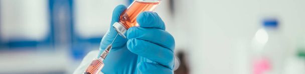обрезанный вид биохимика, принимающего лекарства из стеклянного контейнера со шприцем, панорамный снимок
 - Фото, изображение