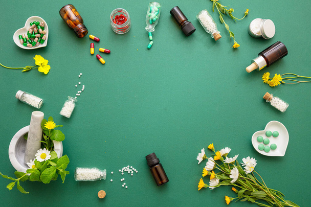 Alternatif bitkisel ilaç. Homeopatik küreler, taze yabani çiçekler ve yeşil arka planda düzleşmiş otlar. Aromaterapi, Homeopati doğal ürünleri. - Fotoğraf, Görsel