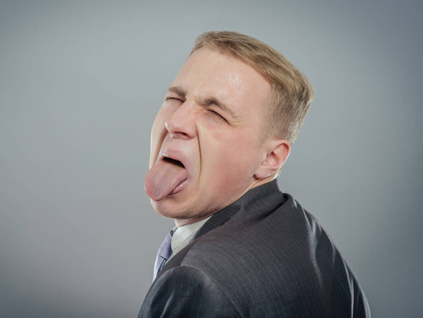 Closeup portrait funny annoyed young childish rude bully man sticking his tongue out at you camera gesture, isolated gray background. Negative emotion facial expression feelings, signs, symbols - Foto, imagen